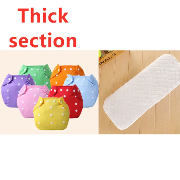 Colorful reusable cloth diapers with white snaps and a thick white quilted diaper insert on wooden floor