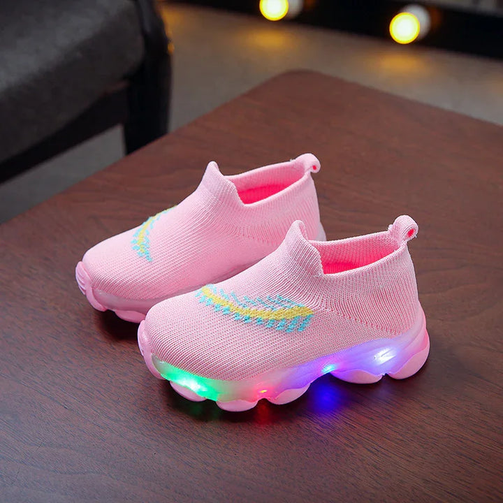 Pink toddler light-up sneakers with knitted upper and colorful sole lights on wooden table