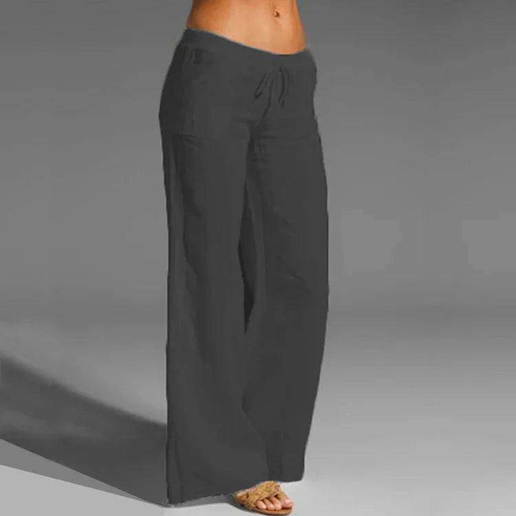Woman wearing loose black drawstring pants and sandals on gray background