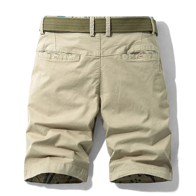 Beige casual chino shorts with back pockets and olive green woven belt on white background