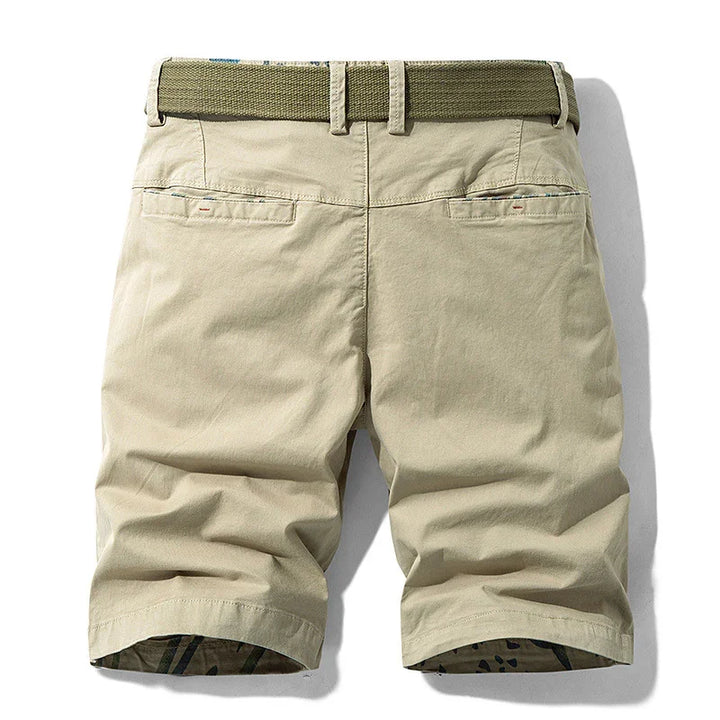 Beige casual chino shorts with back pockets and olive green woven belt on white background