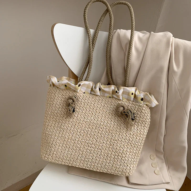 Beige woven summer tote bag with floral ruffled fabric lining, hanging on chair with cream blazer