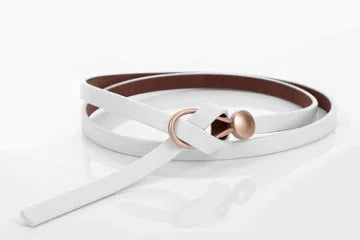White leather belt with rose gold buckle on reflective white surface