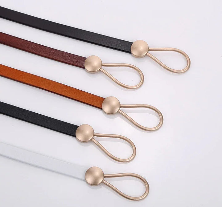 Five slim leather belts in black, brown, tan, black, and white with gold round loop buckles on white background