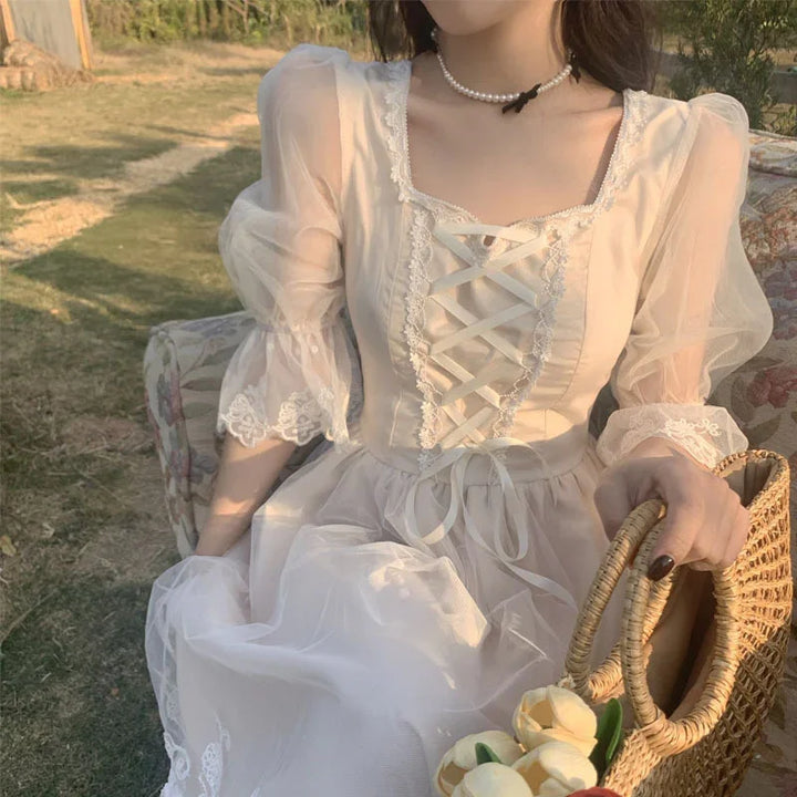 Woman in a white lace-up dress with sheer puff sleeves holding a wicker bag with yellow flowers outdoors