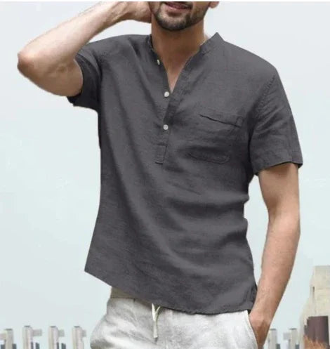 Man wearing short-sleeve charcoal gray henley shirt with buttons and chest pocket, light pants