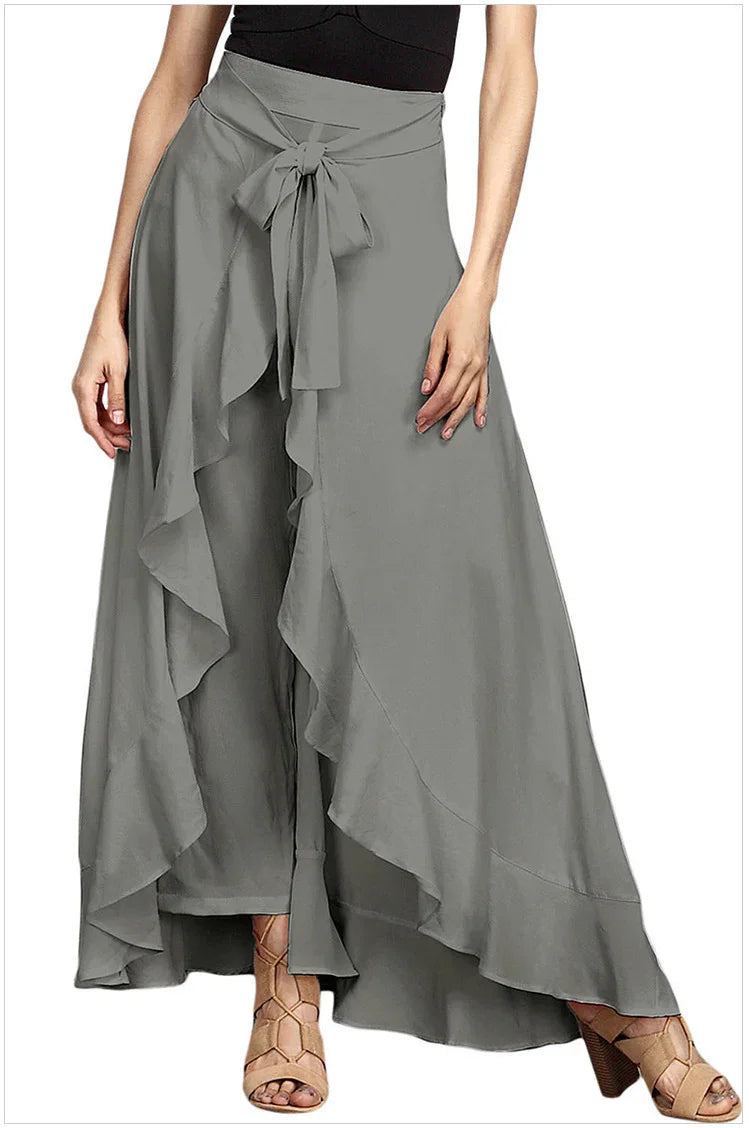 Woman wearing gray high-waisted wide-leg pants with ruffle overlay and front tie belt