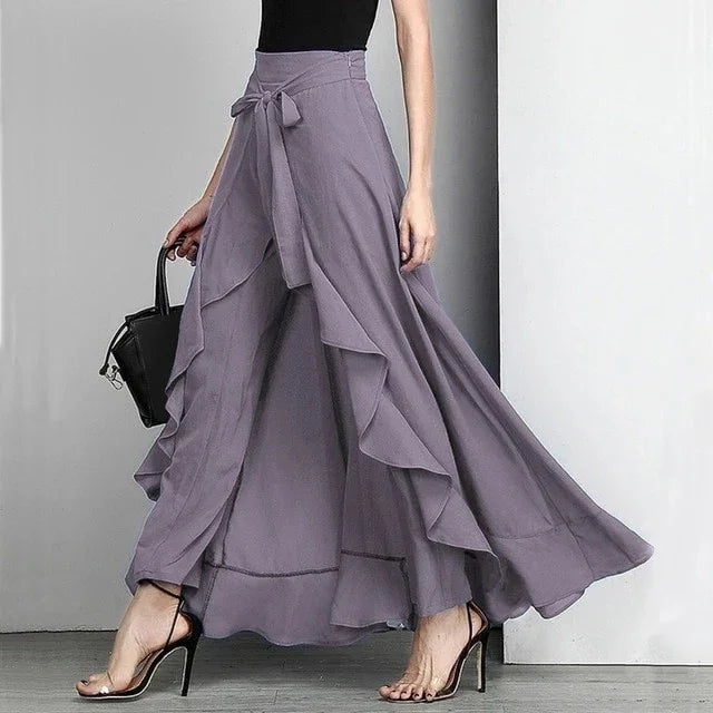 Woman wearing flowing lavender wide-leg pants with ruffle details and a tie waist, paired with black heels
