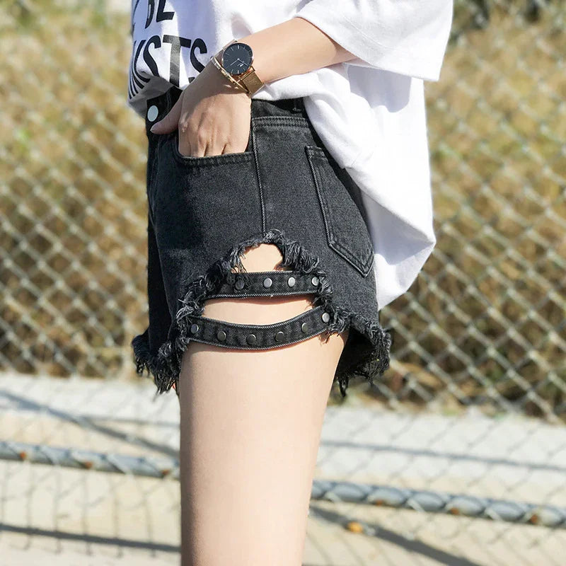 Black distressed denim shorts with studded cutouts, worn with white oversized t-shirt and gold watch