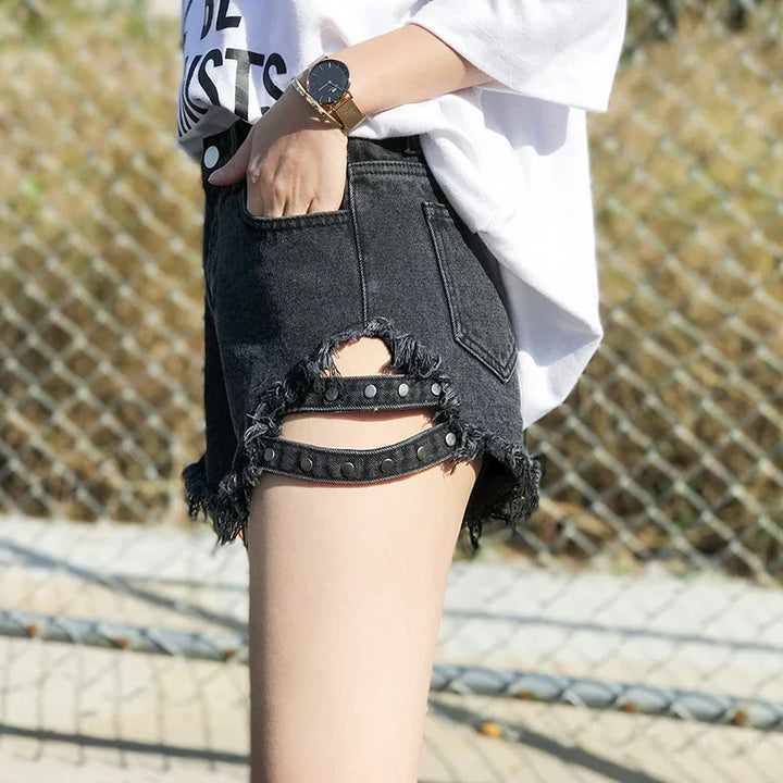 Black distressed denim shorts with studded cutouts, worn with white oversized t-shirt and gold watch