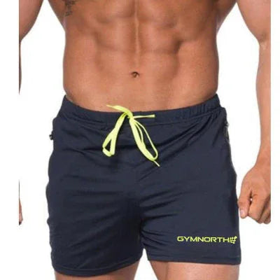 Muscular man wearing black Gymnorth swim shorts with neon yellow drawstring and logo