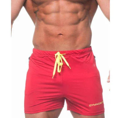 Muscular man wearing red Gymcraft shorts with yellow drawstring against white background