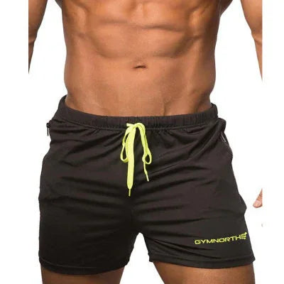 male model wearing black Gymnorth shorts with neon yellow drawstring and logo, showing toned abs