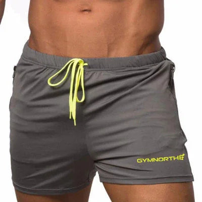 Close-up of a man wearing gray Gymnorth shorts with neon yellow drawstring and logo on white background