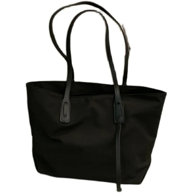 Black tote bag with long handles and minimalist design on white background