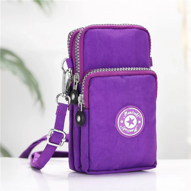 Compact purple crossbody bag with multiple zippered compartments and adjustable strap