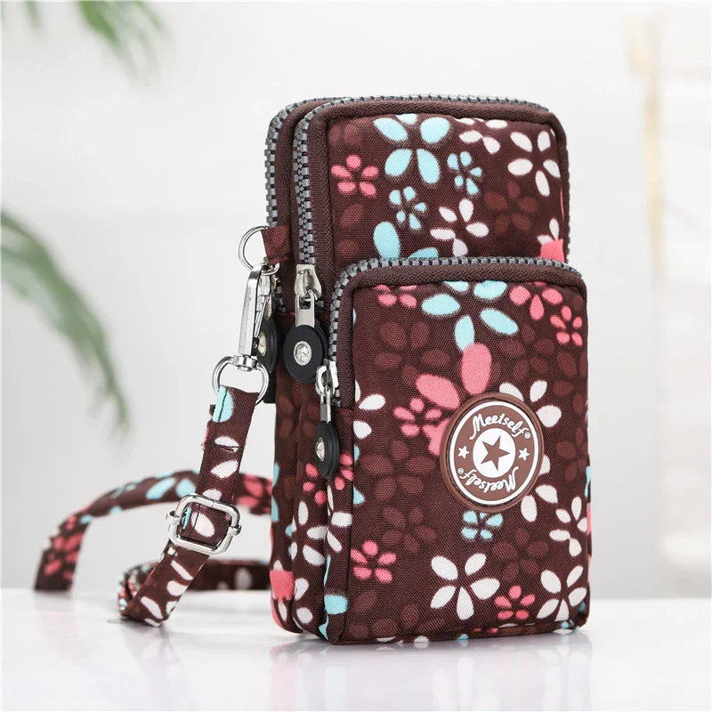 Brown floral crossbody bag with pink, blue, and white flowers and multiple zippered compartments