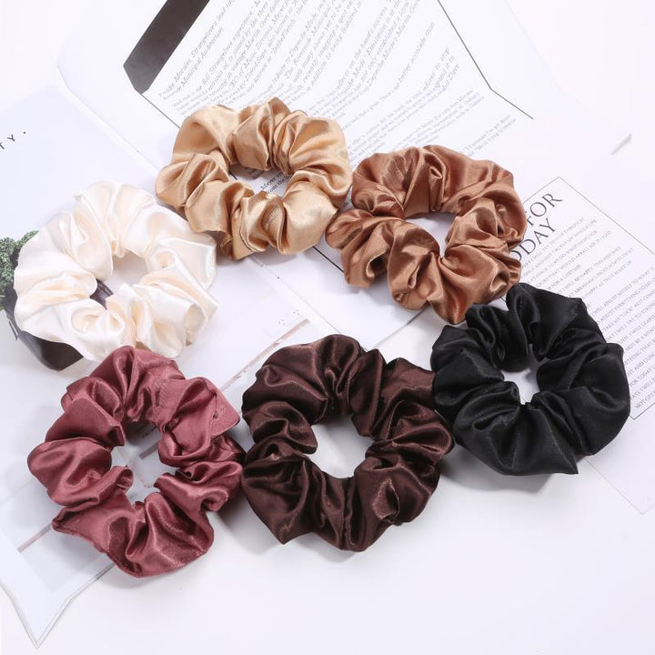 Set of six satin scrunchies in cream, beige, brown, black, pink, and chocolate colors on white background