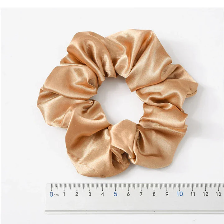 golden satin scrunchie hair tie next to a 15cm ruler on white background