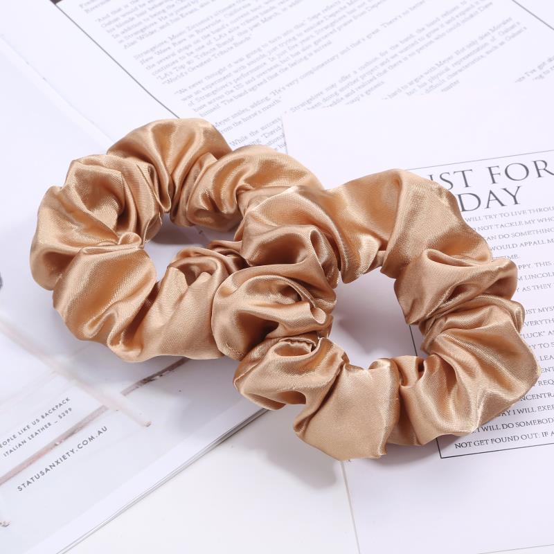 Two beige satin hair scrunchies on open magazine pages
