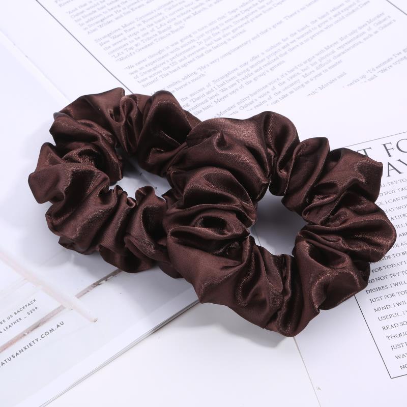 Two dark brown satin scrunchies on an open magazine page