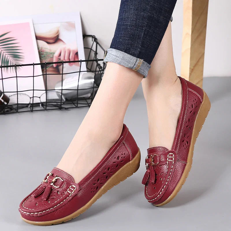 Women wearing casual red leather loafers with tassel details and perforated patterns, paired with rolled-up jeans