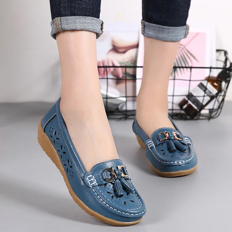 Blue leather loafers with tassels and cut-out floral design worn with rolled-up dark jeans