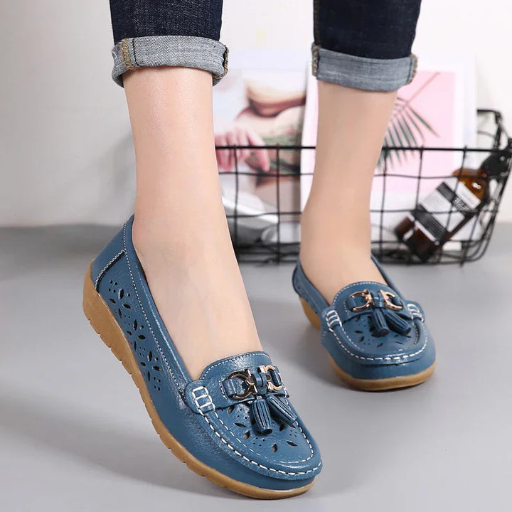 Blue leather loafers with tassels and cut-out floral design worn with rolled-up dark jeans