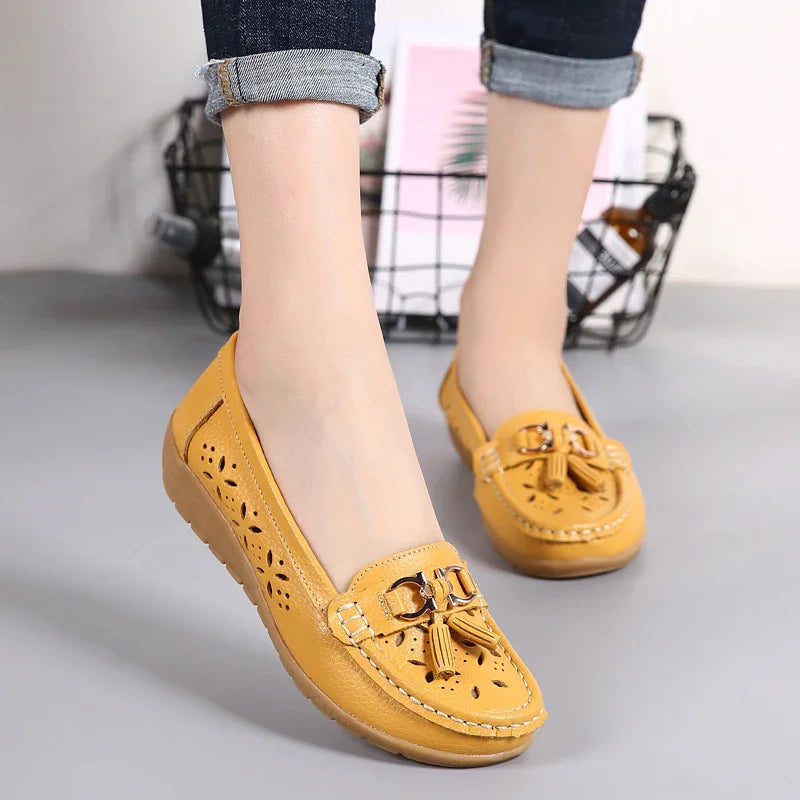 Women's mustard yellow leather loafers with tassel accents and cutout floral design