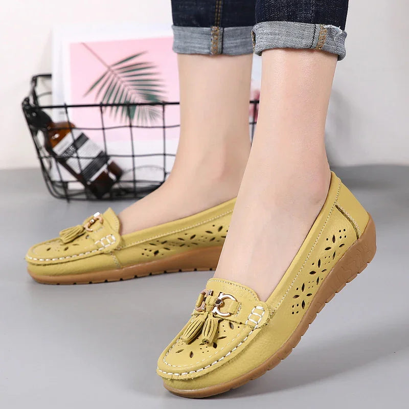Yellow women's casual loafers with tassels and perforated floral design, worn with rolled-up jeans