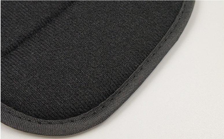 Close-up of black textured fabric edge with reinforced binding on light surface