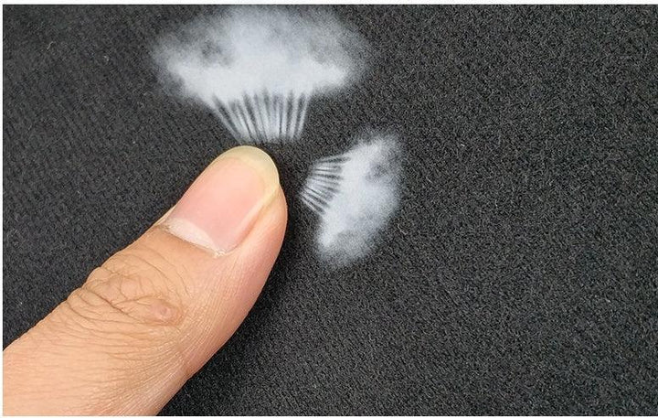 Close-up of finger touching black fabric showing white color transfer marks