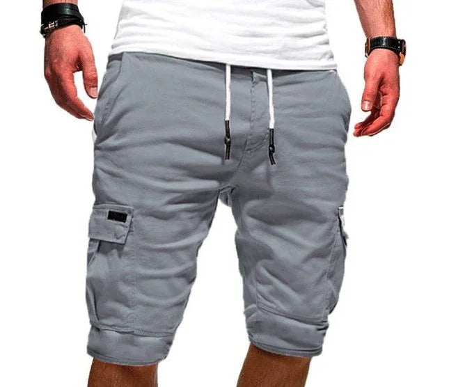 Men's gray cargo shorts with drawstring waist and flap pockets worn with white t-shirt