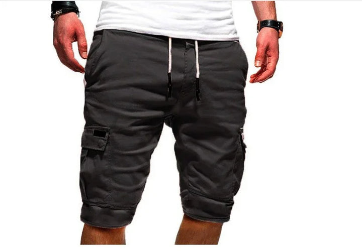 Man wearing black cargo shorts with pockets and white drawstring, paired with a white t-shirt and wristwatch