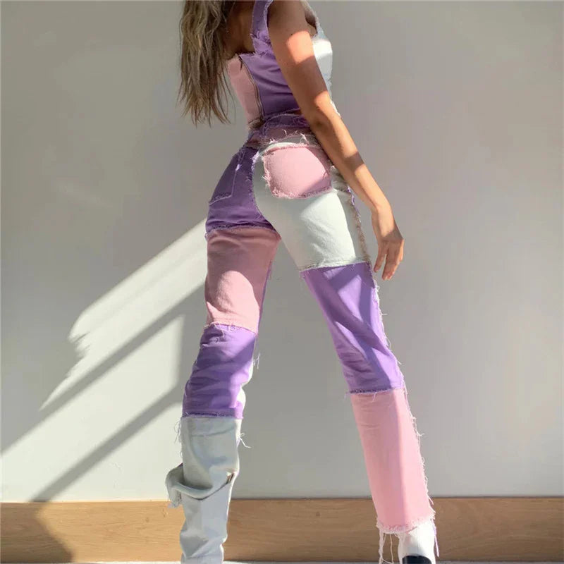Woman wearing patchwork pink, purple, and white distressed jeans with light gray boots against white wall