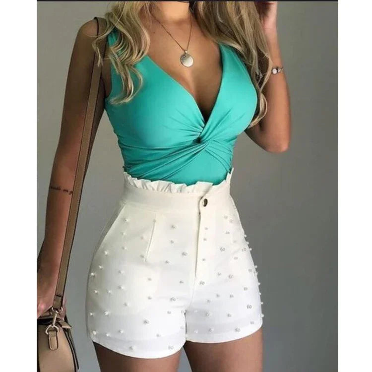 Woman wearing turquoise sleeveless top and high-waisted white shorts with pearl embellishments