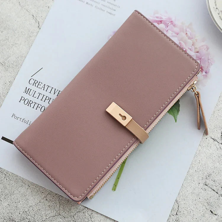 Pink leather wallet with gold lock detail on a magazine page featuring a flower image