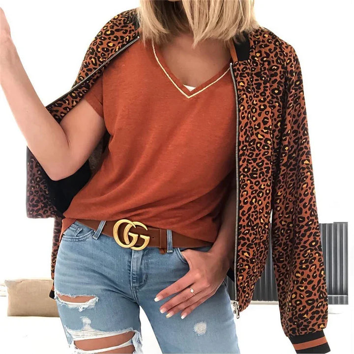 Woman wearing rust orange V-neck top, leopard print jacket, ripped light blue jeans, and brown Gucci belt