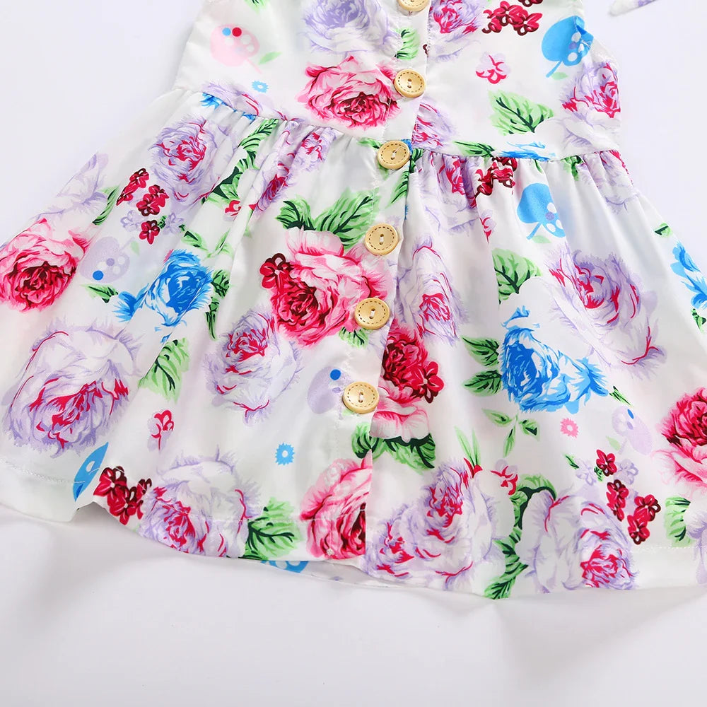 White baby dress with colorful pink, blue, and purple floral print and wooden buttons down the front
