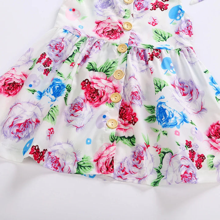 White baby dress with colorful pink, blue, and purple floral print and wooden buttons down the front