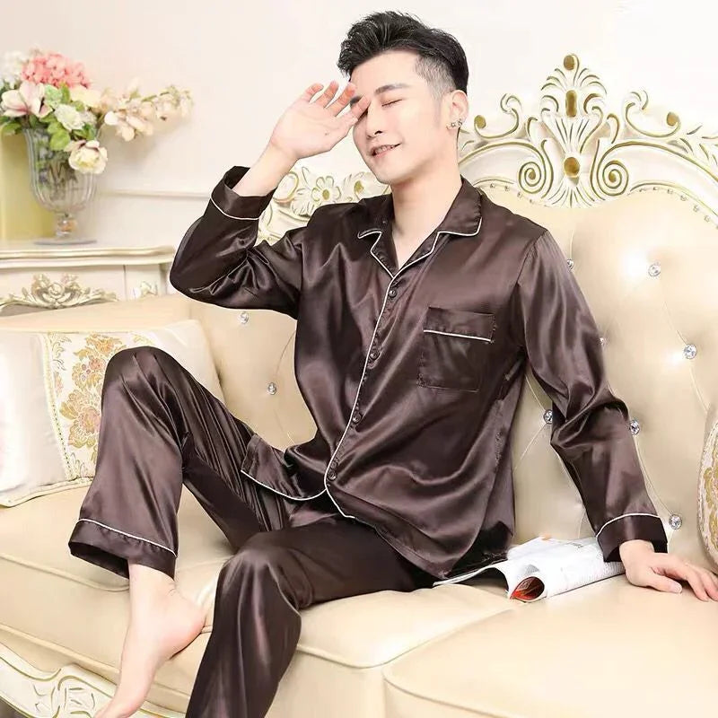 man relaxing on ornate cream sofa wearing dark brown satin pajamas with magazine