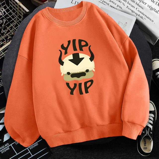 Orange sweatshirt featuring cartoon character with white hair and horns, text 'YIP YIP' graphic design