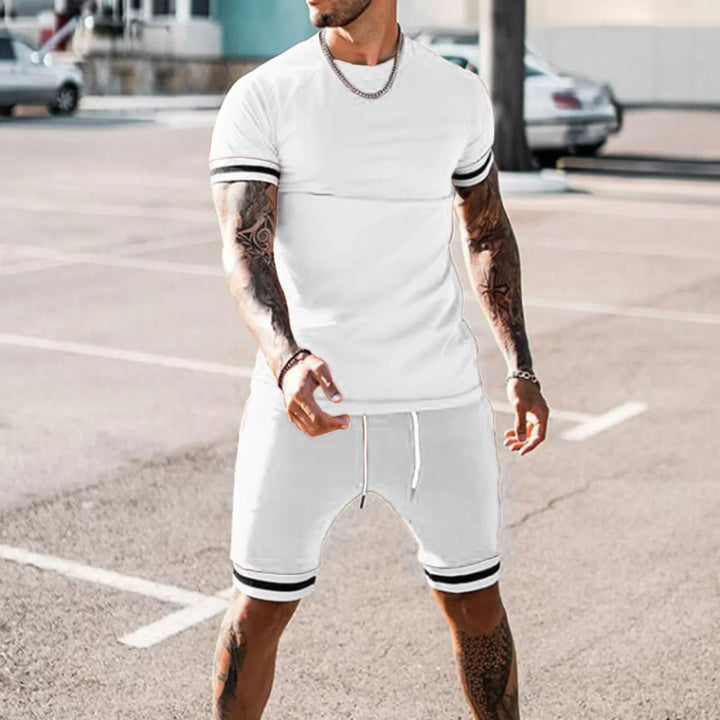 Man with tattoos wearing white sporty shorts and t-shirt with black stripes in outdoor parking lot