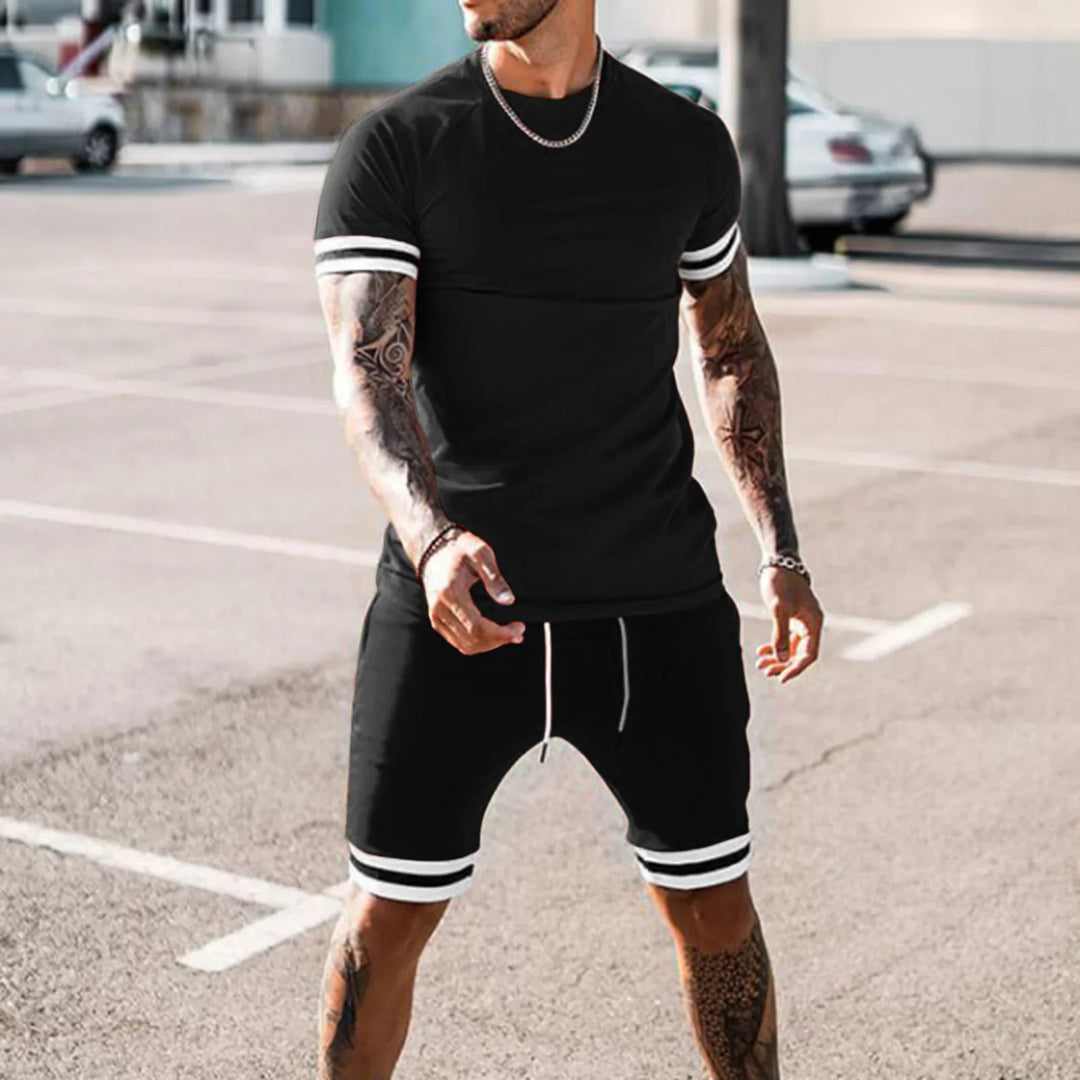 Man in black athletic t-shirt and shorts with white stripes posing outdoors in parking lot