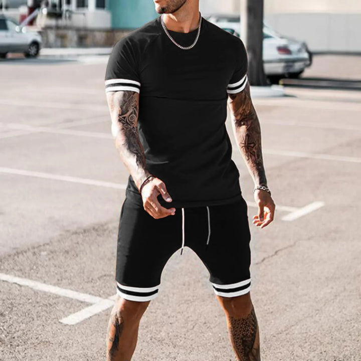 Man in black athletic t-shirt and shorts with white stripes posing outdoors in parking lot