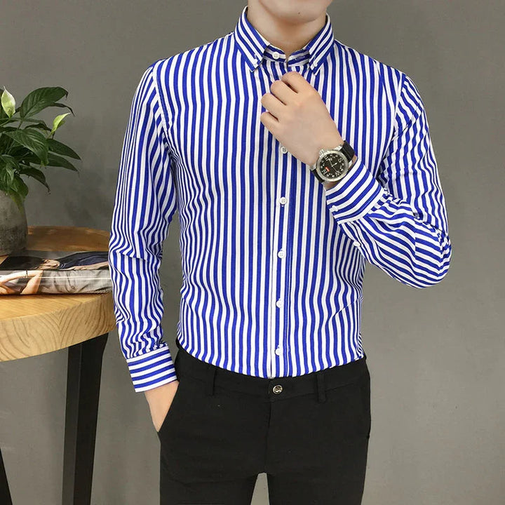 Man wearing blue and white vertical striped dress shirt with black pants and wristwatch indoors