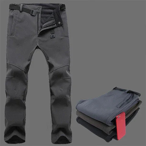 Black outdoor hiking pants with knee padding and belt, folded pants with red smartphone on grey background