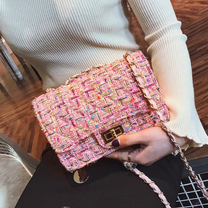 Person holding pink tweed chain strap handbag with gold clasp, wearing cream ribbed long sleeve top