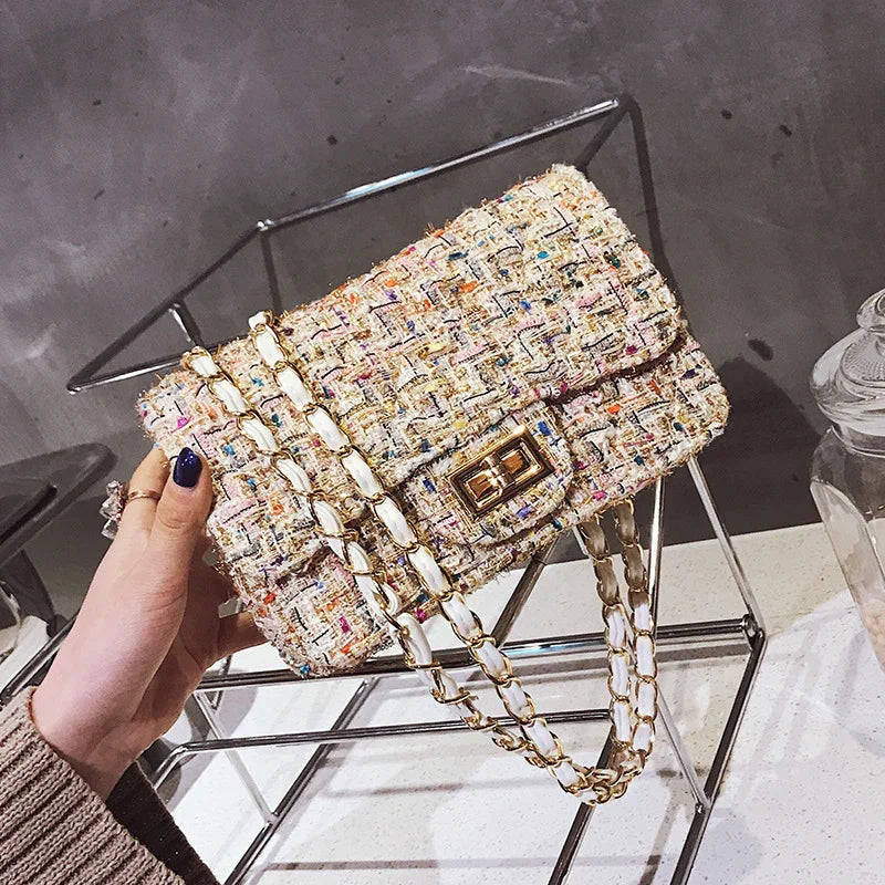 Hand holding a colorful tweed chain shoulder bag with gold and white links on metal frame
