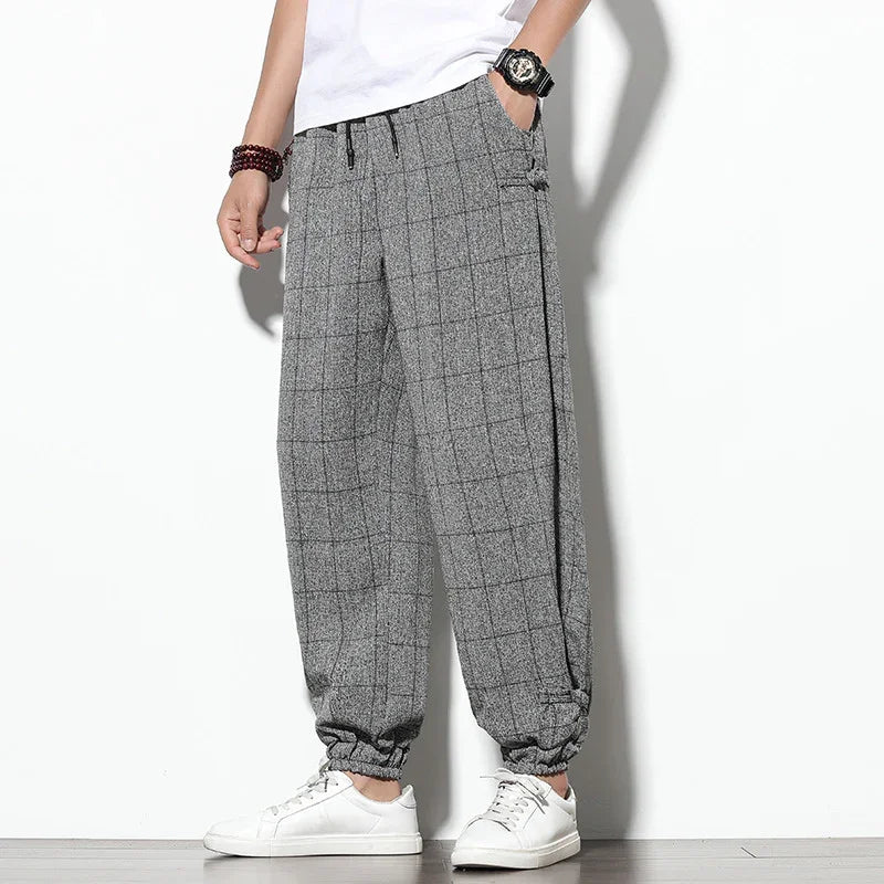 Men's grey checkered casual pants with elastic cuffs paired with white sneakers